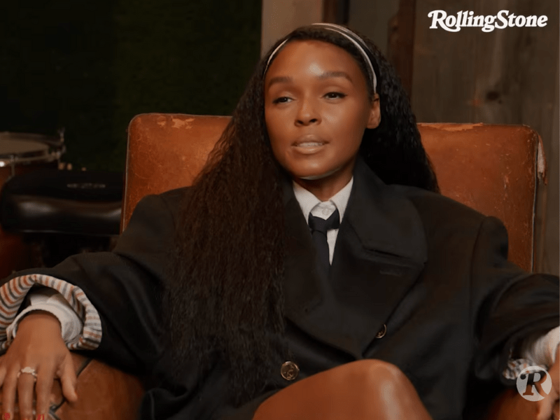Janelle Monáe sitting on a brown sofa