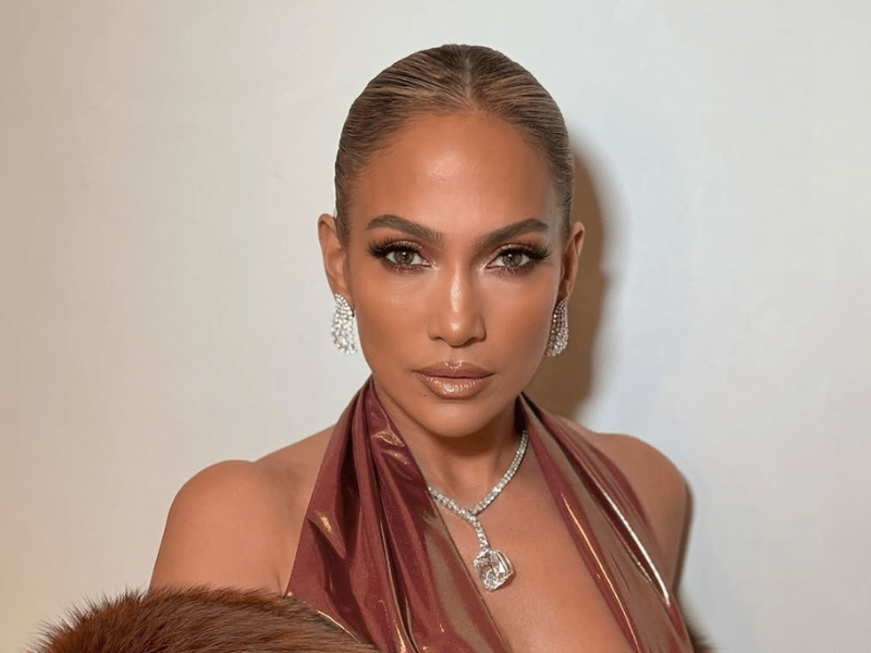 Jennifer Lopez's hair is styled in a slicked back bun with a middle part