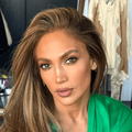 Jennifer Lopez wearing a green silk gown while sitting in a make up chair