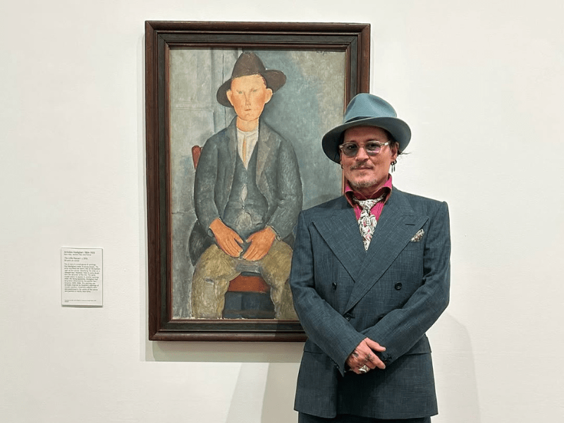 Johnny Depp poses next to a painting of The Little Peasant