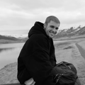Justin Bieber sitting in an outdoor, mountainous landscape