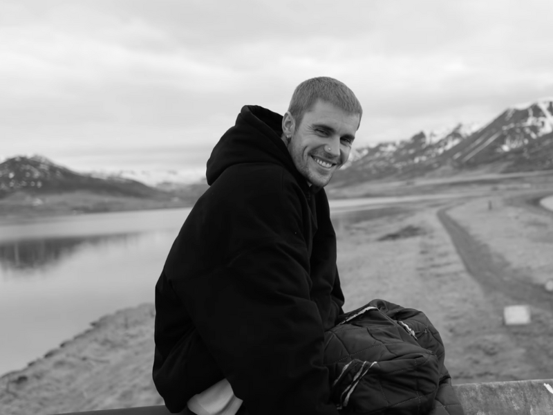 Justin Bieber sitting in an outdoor, mountainous landscape