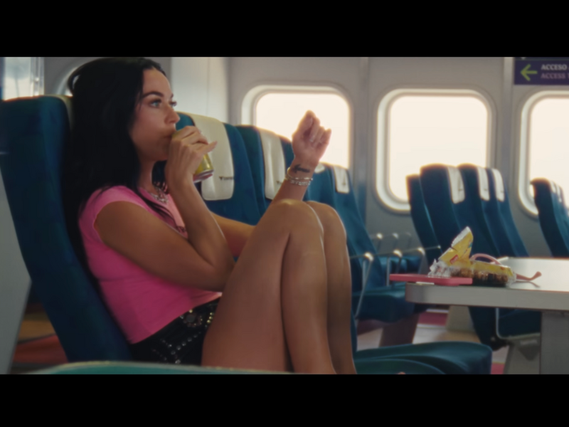 Katy Perry sips on a drink while sitting on a blue boat seat