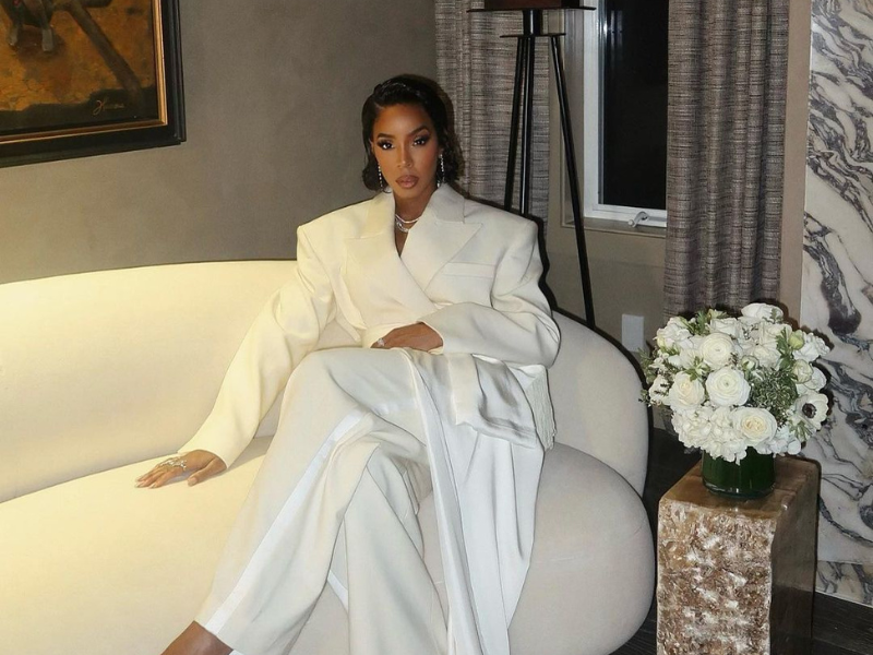 Kelly Rowland sits on a white sofa