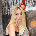 Kesha poses next to w wall covered in graffiti