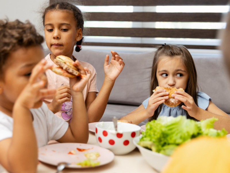 Kids enjoying eating burgers in at the dining table