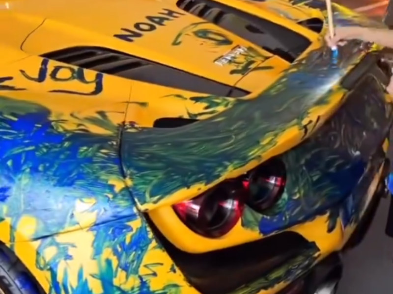 Kids paint a yellow Ferrari 812 at a party