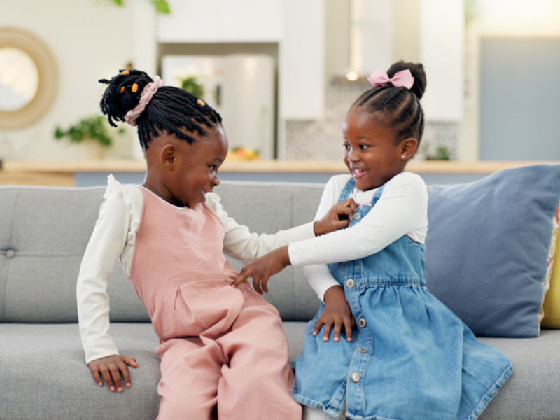 Kids playfully poke one another on the couch