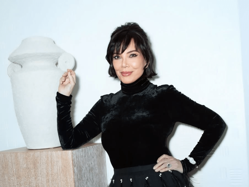 Kris Jenner poses next to a textured white vase with urn handles
