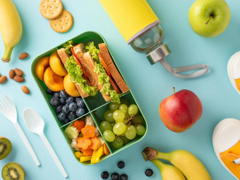 Lunchbox with food and fruit and school stationery