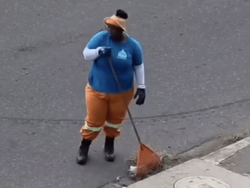 MUNICIPAL WORKER SWEEPING LITTER DOWN DRAIN