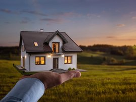 Male hand holding a new dream house at the empty field