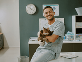 Male vet holds a cat in veterinary office