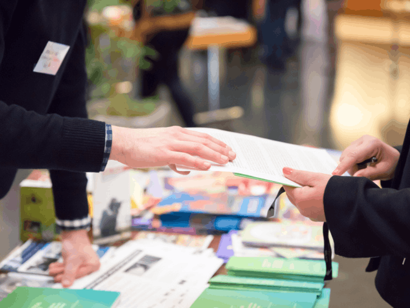 Man and woman sharing information leaflet over exhibition stand