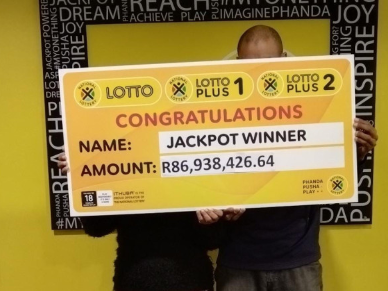 Man and lady stand with their lottery winning cheque