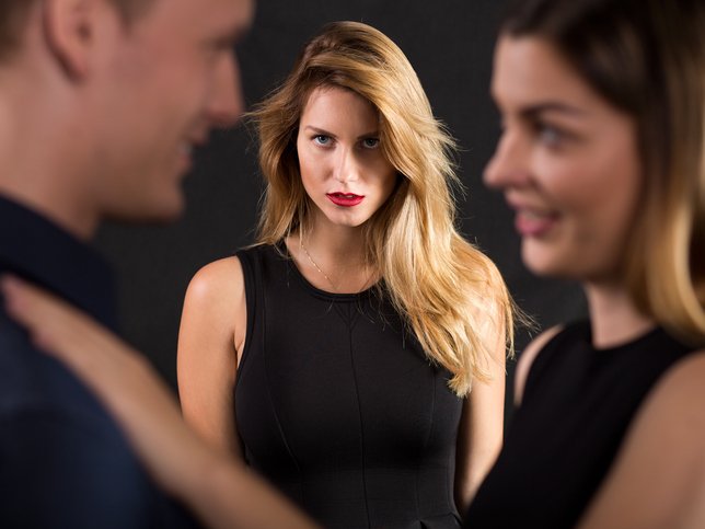 Man and woman talking while another one looks at them with envy