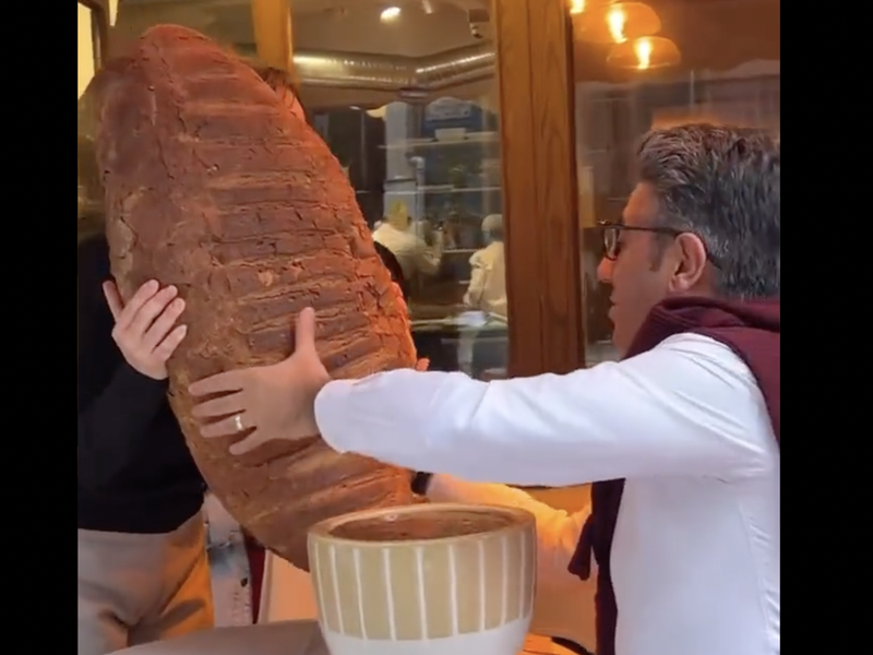 Man eats massive croissant at restaurant