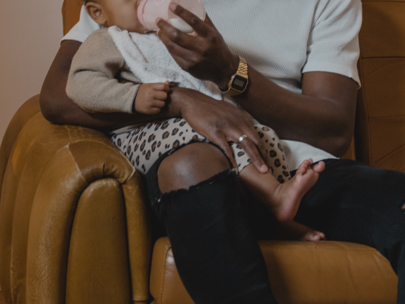 Man feeding his daughter while sitting on sofa