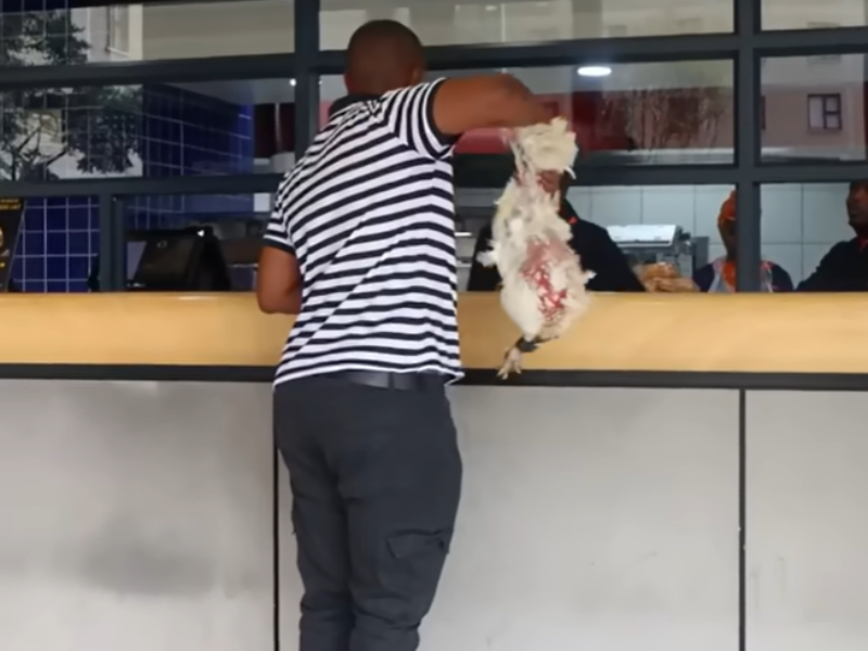 Man holding live chicken at food outlet