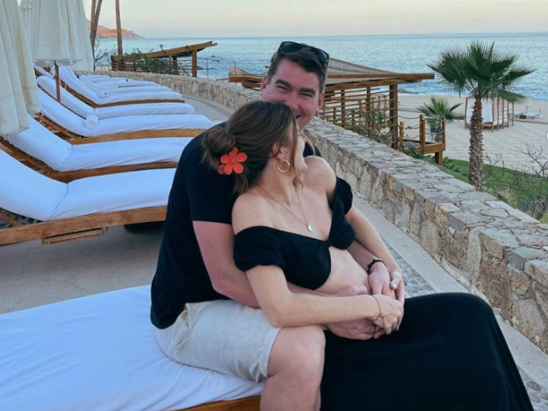 Man holds woman while sitting on a beach relaxing chair