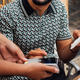 Man in black and white button up shirt smiling at woman and paying for bill at restaurant