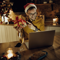 Man holding Christmas present while chatting on laptop