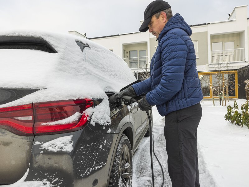 Man putting petrol in car at his home during snow