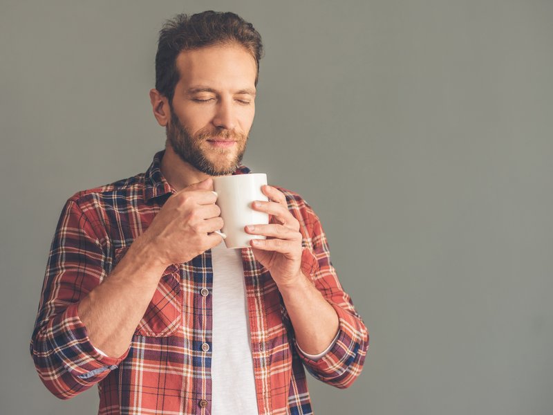 Man smelling a cup of hot beverage iStock