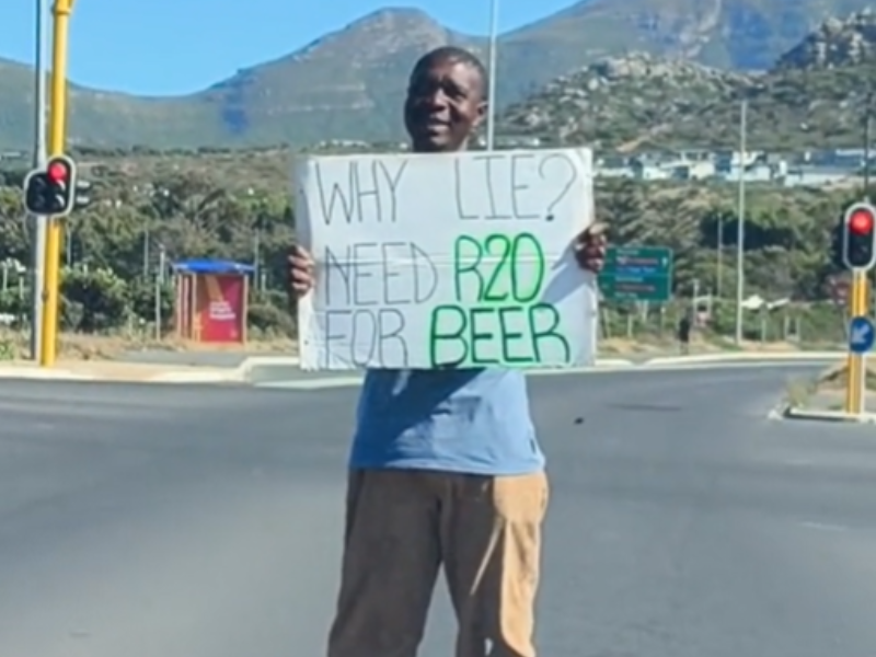 Man standing at the traffic lights with placard begging