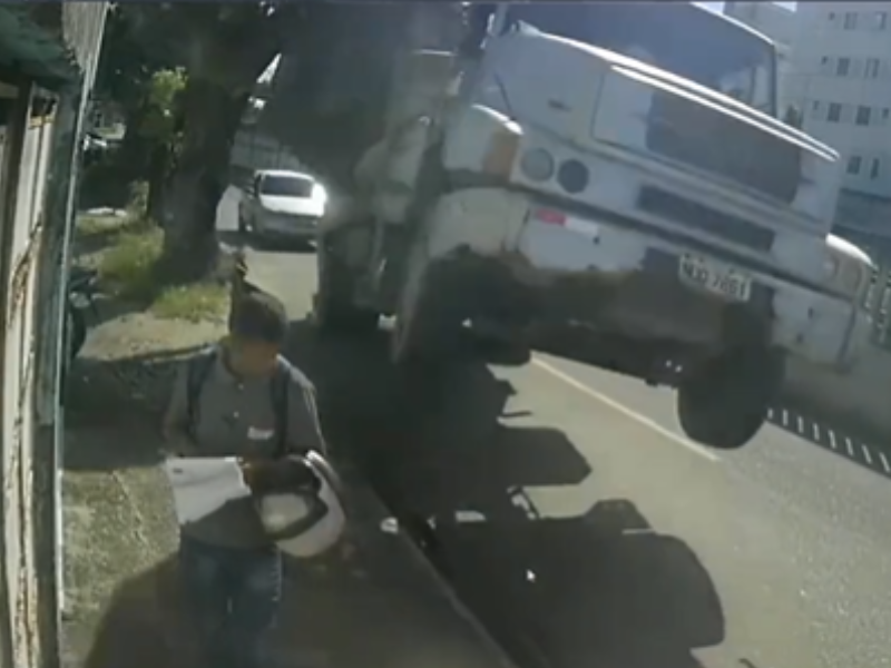 Man standing on side of the road almost crushed by a truck