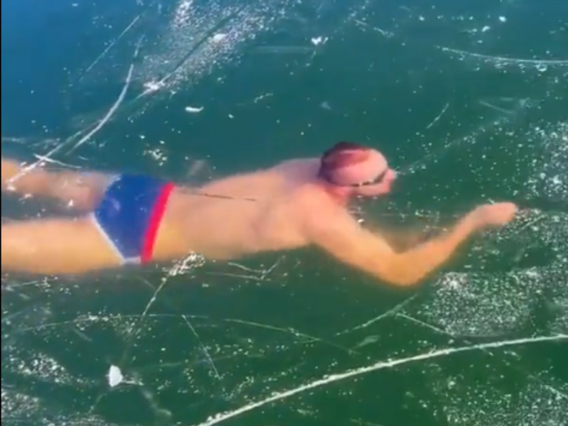 Man swimming inside frozen lake