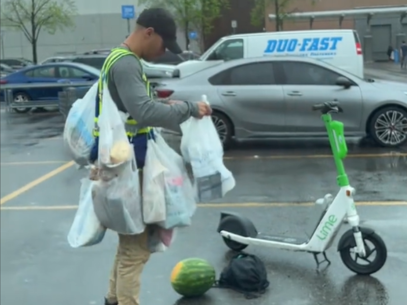 Man uses hooks and baby carrier to carry groceries on scooter