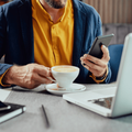 Man using his smartphone and devices and drinking coffee