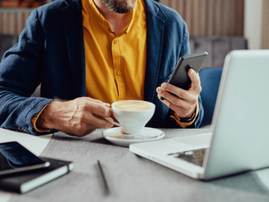 Man using his smartphone and devices and drinking coffee