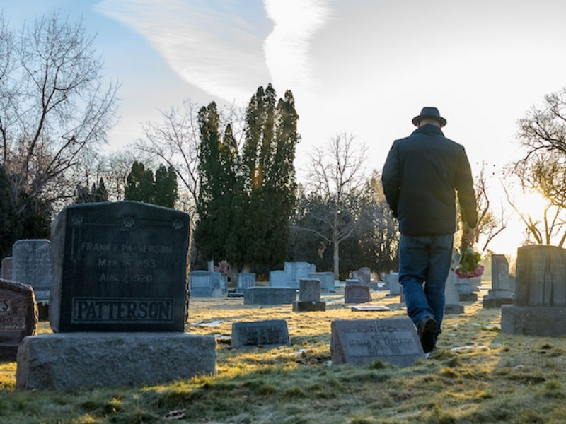 Man walking on green grass at graveyard