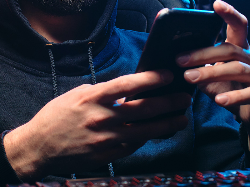 Man with black hoodie sweater using a mobile phone