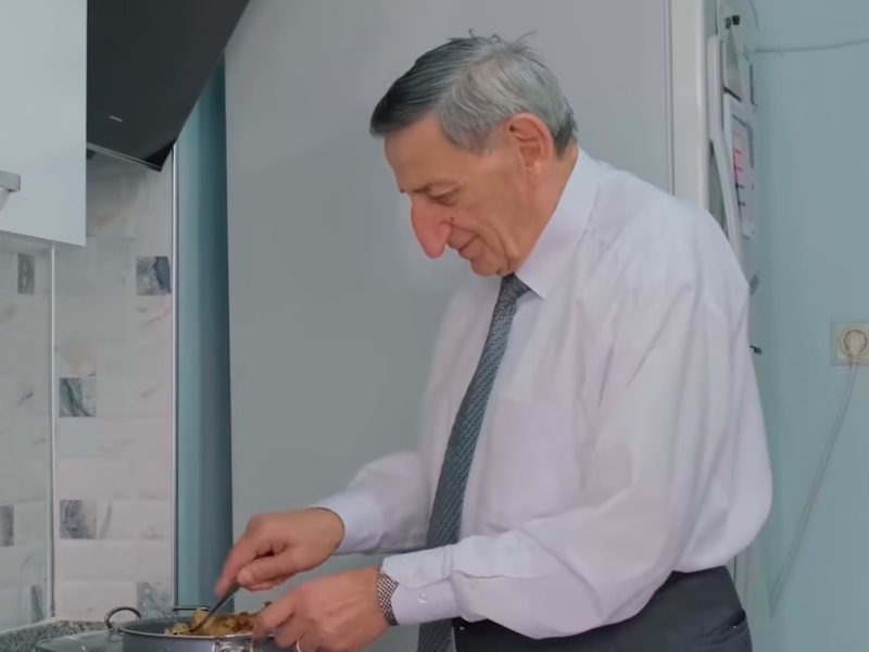 Man with long nose looking down at stove top