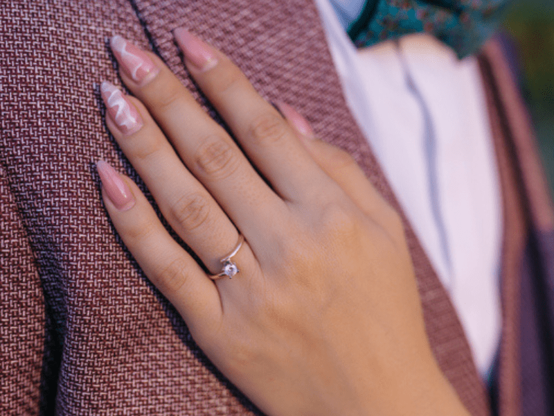 Manicured hand with a gold ring rests on man's jacket