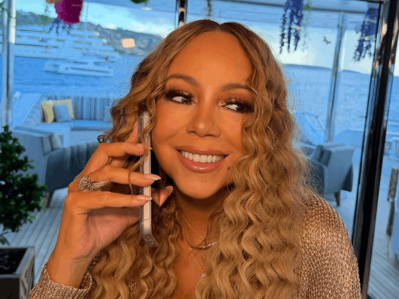 Mariah Carey holds a phone to her hear
