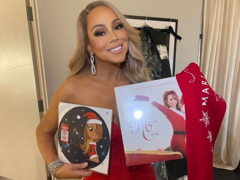 Mariah Carey standing with her All I Want for Christmas record