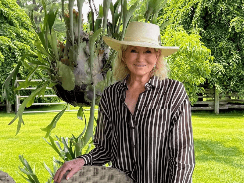 Martha Stewart poses outdoors in a green garden setting
