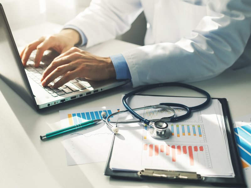 Doctor working with medical statistics and financial reports in office