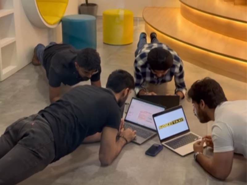 Men plank in front of their laptops in an office meeting