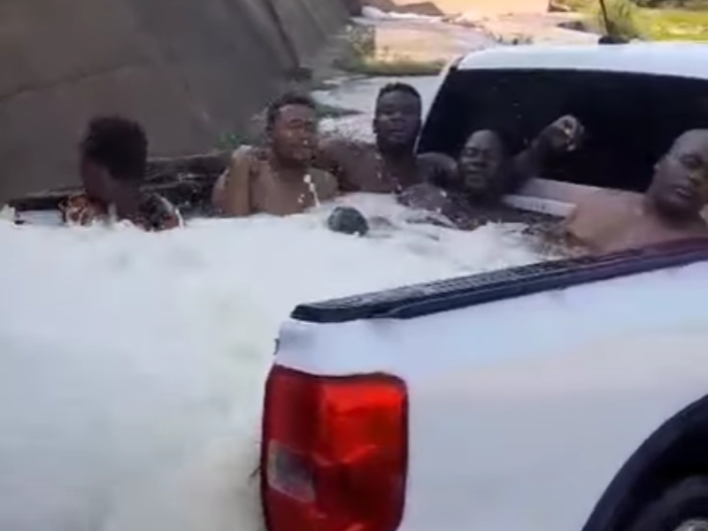 Men relaxing at the back of a bakkie with water gushing in