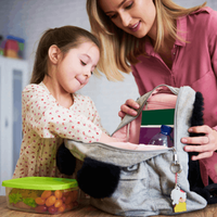 Mom and daughter packing school lunch in a backpack