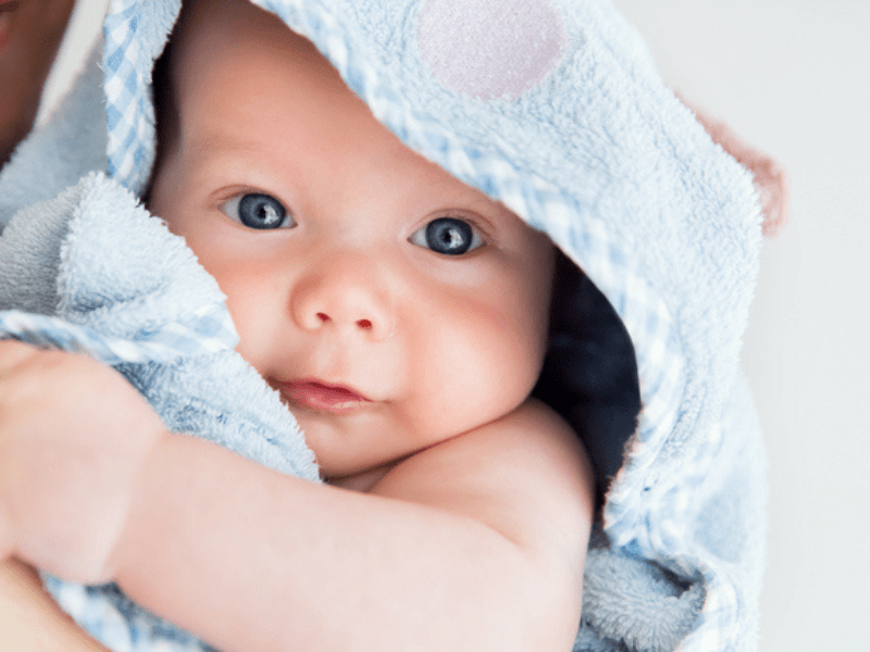 Mom holds a cute baby wrapped in a blue bath towel