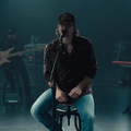Morgan Wallen sitting on a stool while performing