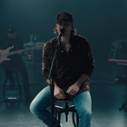 Morgan Wallen sitting on a stool while performing