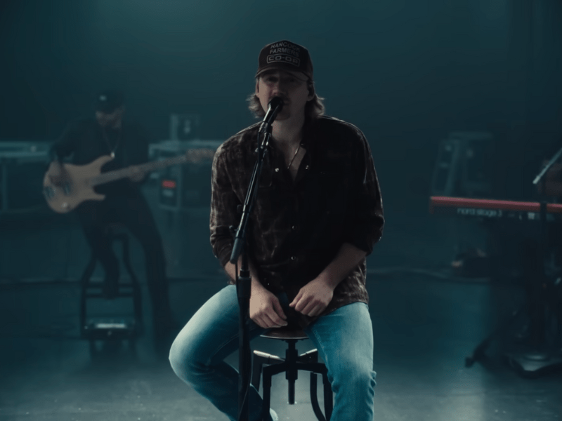 Morgan Wallen sitting on a stool while performing