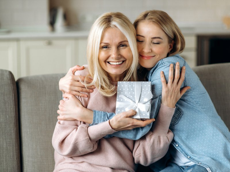 Mother and daughter hugging with gift in hand iStock